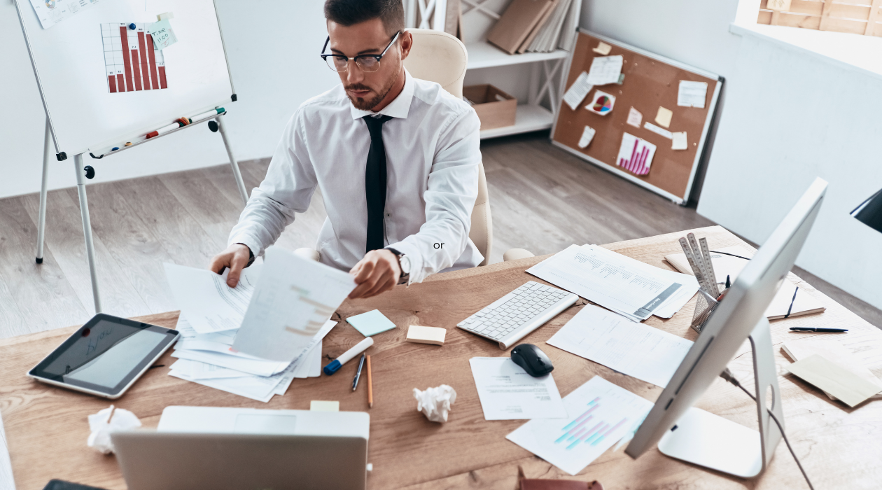 The picture of a pastor busy working at a cluttered desk, in need of a virtual assistant to help. him. 